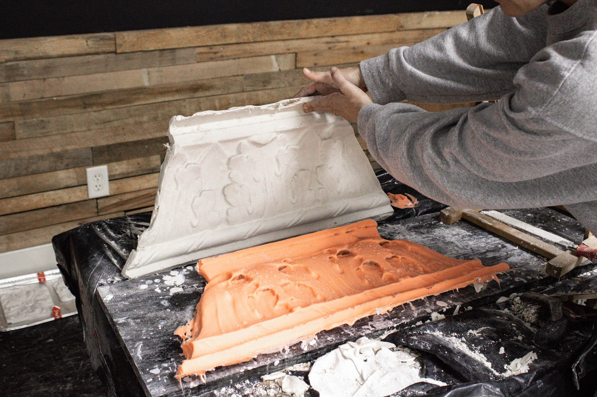 Sculptor Aubrey Charnell in her studio with a new piece of molding and the silicone cast that formed it. 