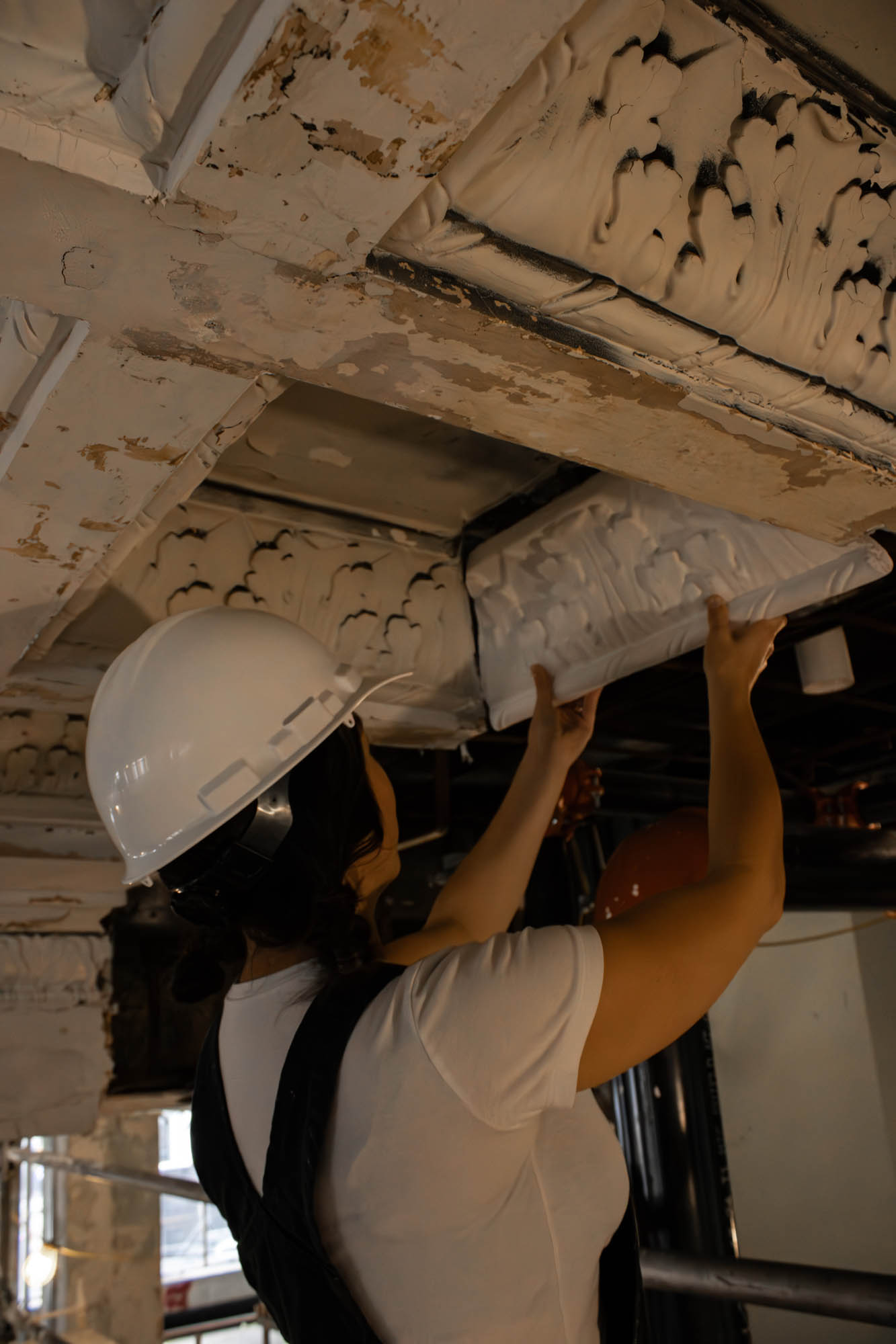 Sculptor Aubrey Charnell holds up a new piece of decorative ceiling molding next to the historic ones. 